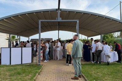 Salle de conférence lumineuse avec tables disposées en U, chaises noires et un tableau noir au fond.