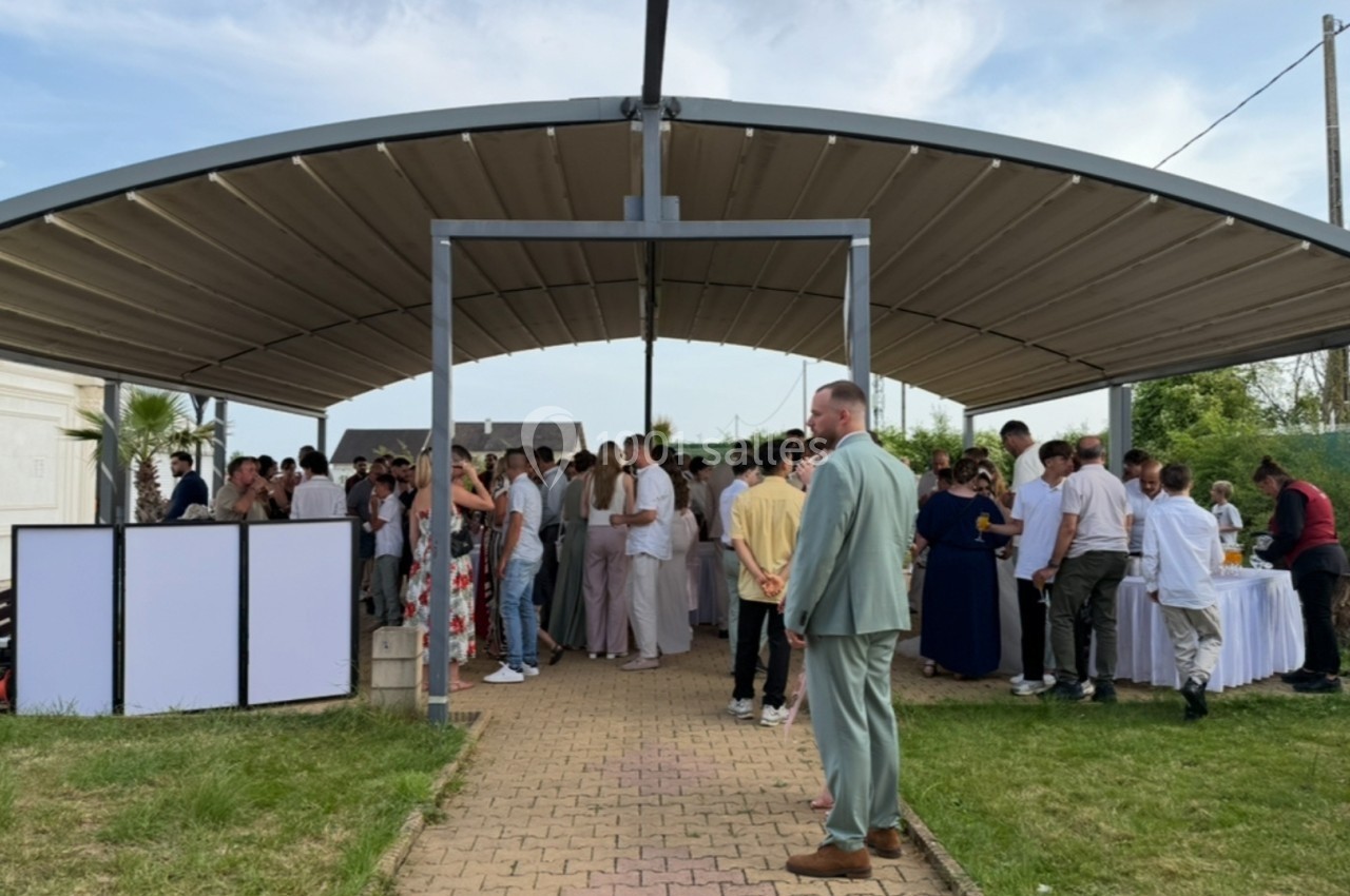 Groupe de personnes rassemblées sous un auvent en plein air, discutant et partageant un moment convivial.