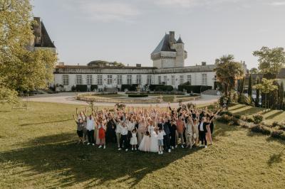 Un couple de mariés s'embrasse devant des invités applaudissant dans une salle de réception lumineuse.
