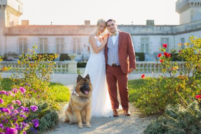Un couple de mariés s'embrasse devant des invités applaudissant dans une salle de réception lumineuse.