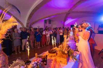 Un couple de mariés s'embrasse devant des invités applaudissant dans une salle de réception lumineuse.