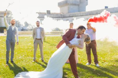 Un couple de mariés s'embrasse devant des invités applaudissant dans une salle de réception lumineuse.