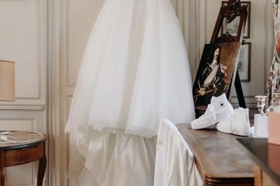 Un couple de mariés s'embrasse devant des invités applaudissant dans une salle de réception lumineuse.