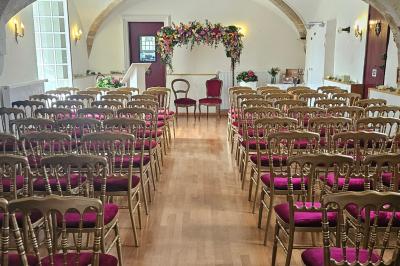 Un couple de mariés s'embrasse devant des invités applaudissant dans une salle de réception lumineuse.