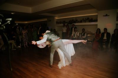 Un couple de mariés s'embrasse devant des invités applaudissant dans une salle de réception lumineuse.