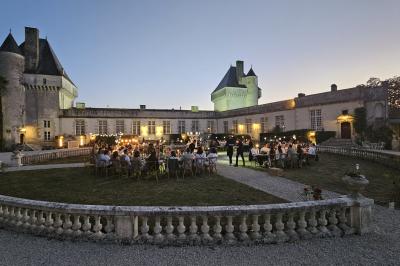 Un couple de mariés s'embrasse devant des invités applaudissant dans une salle de réception lumineuse.