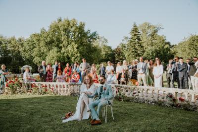 Un couple de mariés s'embrasse devant des invités applaudissant dans une salle de réception lumineuse.