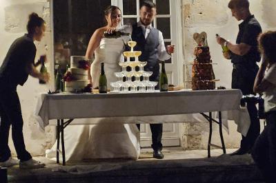 Un couple de mariés s'embrasse devant des invités applaudissant dans une salle de réception lumineuse.