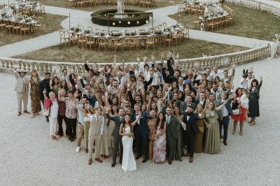 Un couple de mariés s'embrasse devant des invités applaudissant dans une salle de réception lumineuse.