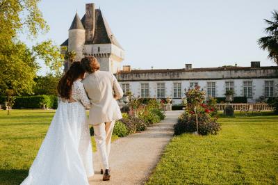 Un couple de mariés s'embrasse devant des invités applaudissant dans une salle de réception lumineuse.