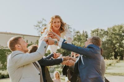 Un couple de mariés s'embrasse devant des invités applaudissant dans une salle de réception lumineuse.