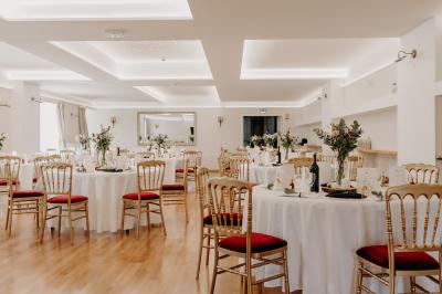 Un couple de mariés s'embrasse devant des invités applaudissant dans une salle de réception lumineuse.