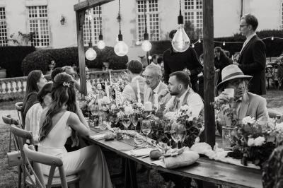 Un couple de mariés s'embrasse devant des invités applaudissant dans une salle de réception lumineuse.