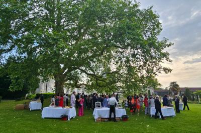 Un couple de mariés s'embrasse devant des invités applaudissant dans une salle de réception lumineuse.