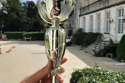 Des personnes en costumes d'époque discutent dans la cour d'un château historique sous un ciel partiellement nuageux.