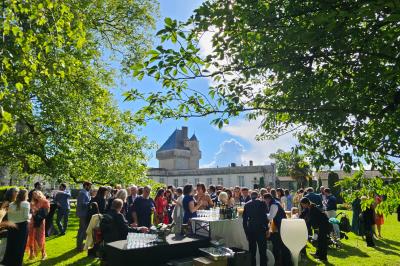 Des personnes en costumes d'époque discutent dans la cour d'un château historique sous un ciel partiellement nuageux.