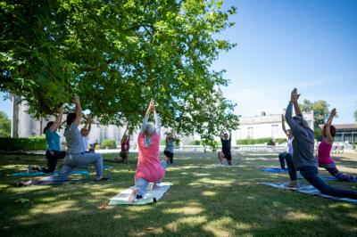 Des personnes en costumes d'époque discutent dans la cour d'un château historique sous un ciel partiellement nuageux.
