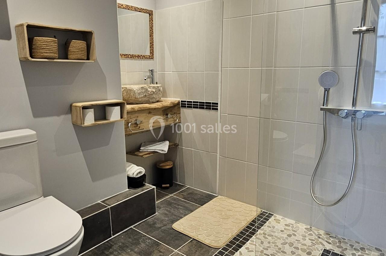 Salle de bain moderne avec douche à l'italienne, toilettes, lavabo en bois et étagères murales.