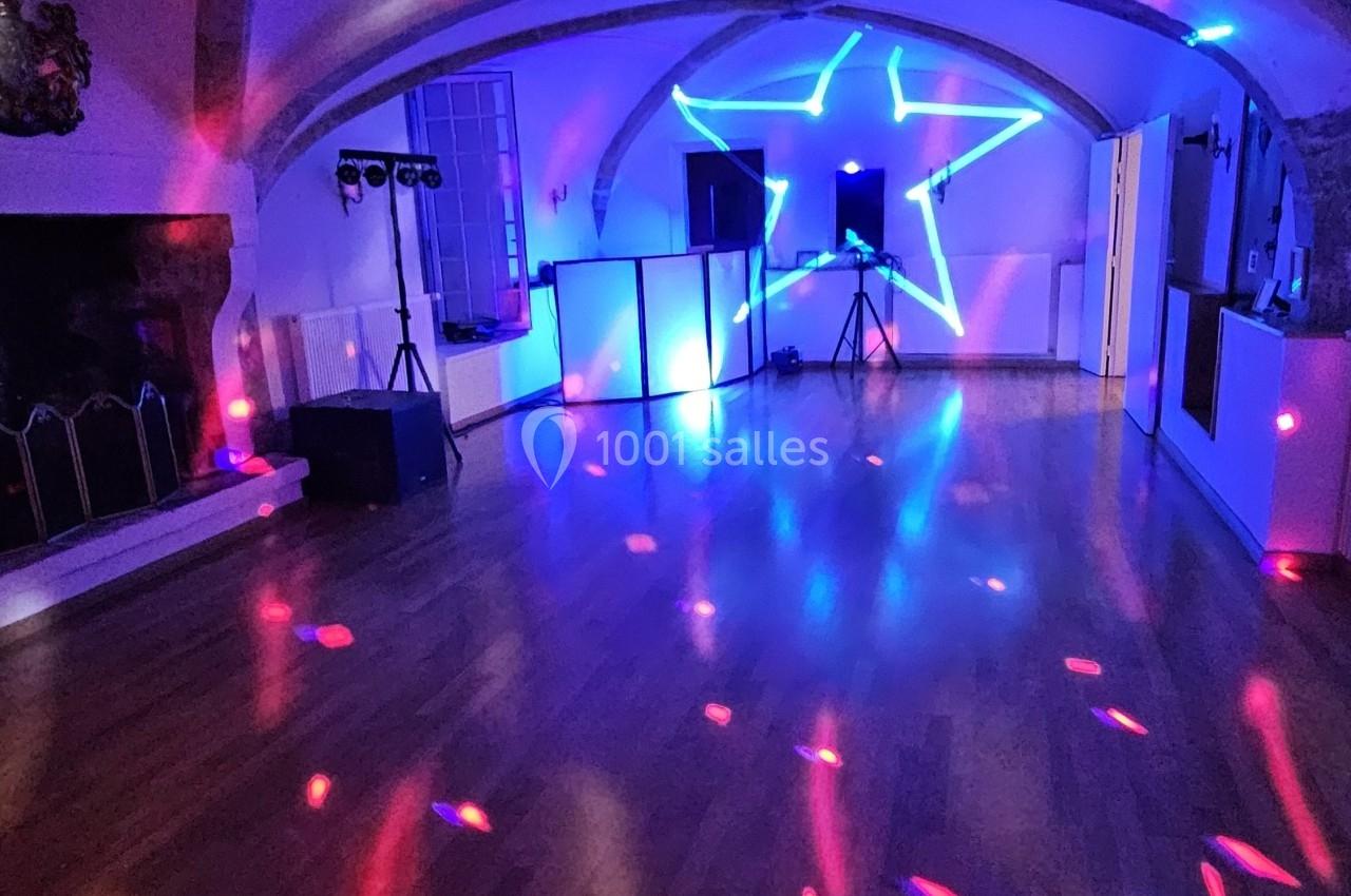 Salle avec éclairage coloré, projecteurs et étoile lumineuse sur un mur, ambiance festive sur parquet.