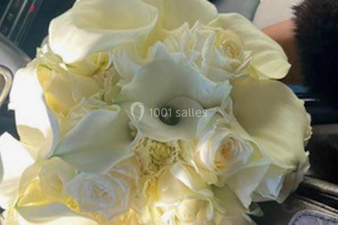 Bouquet de fleurs blanches composé de roses et d'arums, posé sur un siège de voiture.