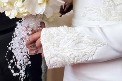 Une mariée en tailleur blanc tenant un bouquet devant une vitrine avec l'inscription ’Love Curated’.
