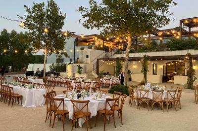 Terrains de padel extérieurs entourés d'arbres et éclairés par des lampadaires, avec un chemin en premier plan.