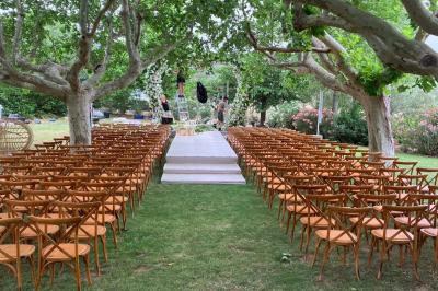 Terrains de padel extérieurs entourés d'arbres et éclairés par des lampadaires, avec un chemin en premier plan.