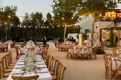 Terrains de padel extérieurs entourés d'arbres et éclairés par des lampadaires, avec un chemin en premier plan.