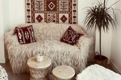 Banquette grise avec coussins rouges à motifs, tables en bois dressées, décor mural avec luminaires et ornements végétaux.