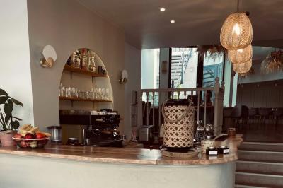 Banquette grise avec coussins rouges à motifs, tables en bois dressées, décor mural avec luminaires et ornements végétaux.