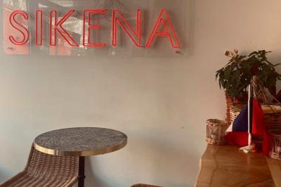 Façade d'un établissement avec vitrines décorées, porte ouverte et panneaux d'information sur le trottoir.