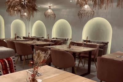 Façade d'un établissement avec vitrines décorées, porte ouverte et panneaux d'information sur le trottoir.