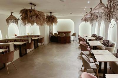 Façade d'un établissement avec vitrines décorées, porte ouverte et panneaux d'information sur le trottoir.