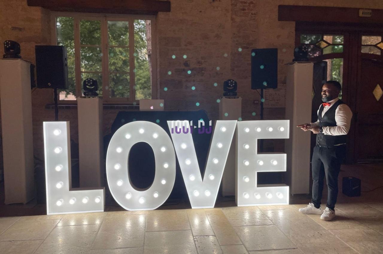 Lettres lumineuses formant le mot ’LOVE’ dans une salle avec un homme debout à côté.