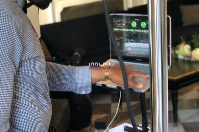 Un DJ souriant derrière une table de mixage avec un ordinateur portable et des équipements audio.