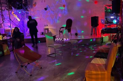 Un DJ souriant derrière une table de mixage avec un ordinateur portable et des équipements audio.