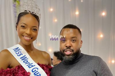 Un DJ souriant derrière une table de mixage avec un ordinateur portable et des équipements audio.