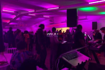 Un DJ souriant derrière une table de mixage avec un ordinateur portable et des équipements audio.