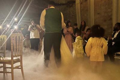 Un DJ souriant derrière une table de mixage avec un ordinateur portable et des équipements audio.