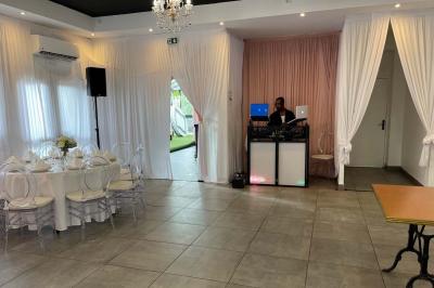 Un DJ souriant derrière une table de mixage avec un ordinateur portable et des équipements audio.