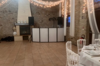 Des personnes dansent dans une salle en pierre éclairée par des lumières colorées, créant une ambiance festive.