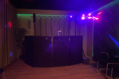 Des personnes dansent dans une salle en pierre éclairée par des lumières colorées, créant une ambiance festive.
