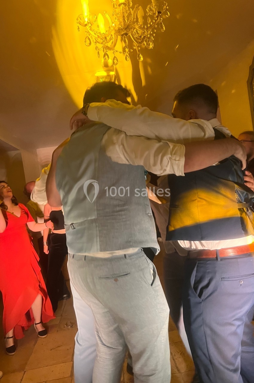 Groupe de personnes dansant et s'enlaçant sous un éclairage jaune lors d'une fête en intérieur.