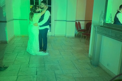 Des personnes dansent dans une salle en pierre éclairée par des lumières colorées, créant une ambiance festive.