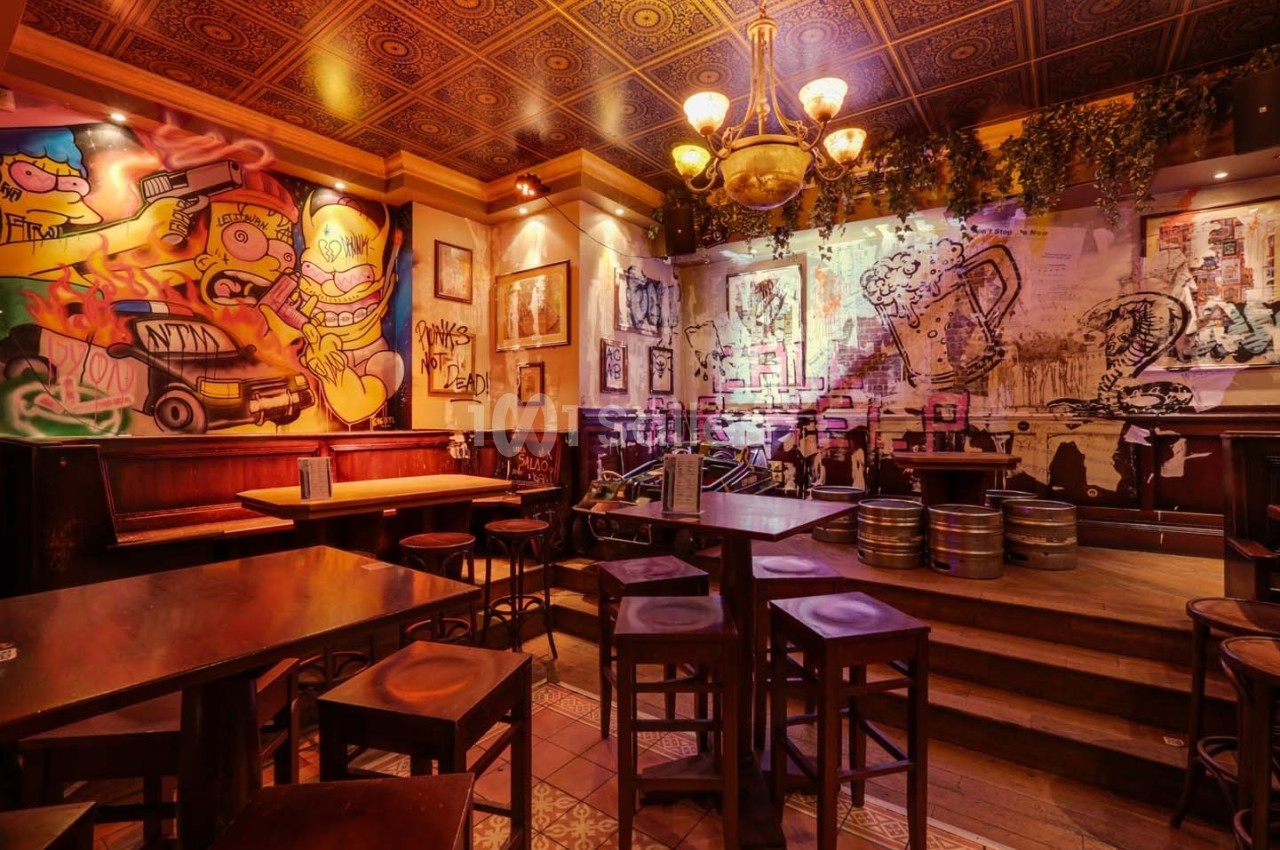 Salle de restaurant avec murs décorés de graffitis colorés, mobilier en bois et ambiance chaleureuse.