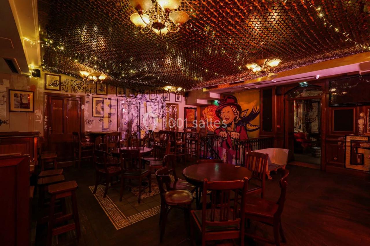 Salle de bar chaleureuse avec mobilier en bois, éclairage tamisé et fresque murale colorée.