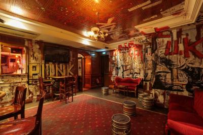 Salle animée avec des personnes dansant sous des lumières colorées, décorée de plantes suspendues et de graffitis.