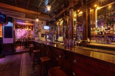 Salle de bar à la décoration punk avec murs graffités, tonneaux métalliques et mobilier en bois et velours rouge.