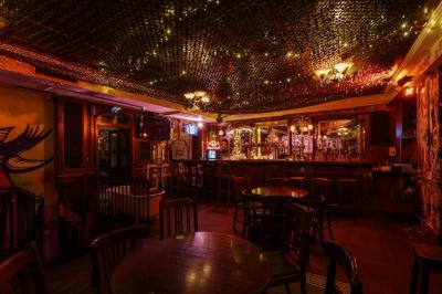 Salle de bar à la décoration punk avec murs graffités, tonneaux métalliques et mobilier en bois et velours rouge.