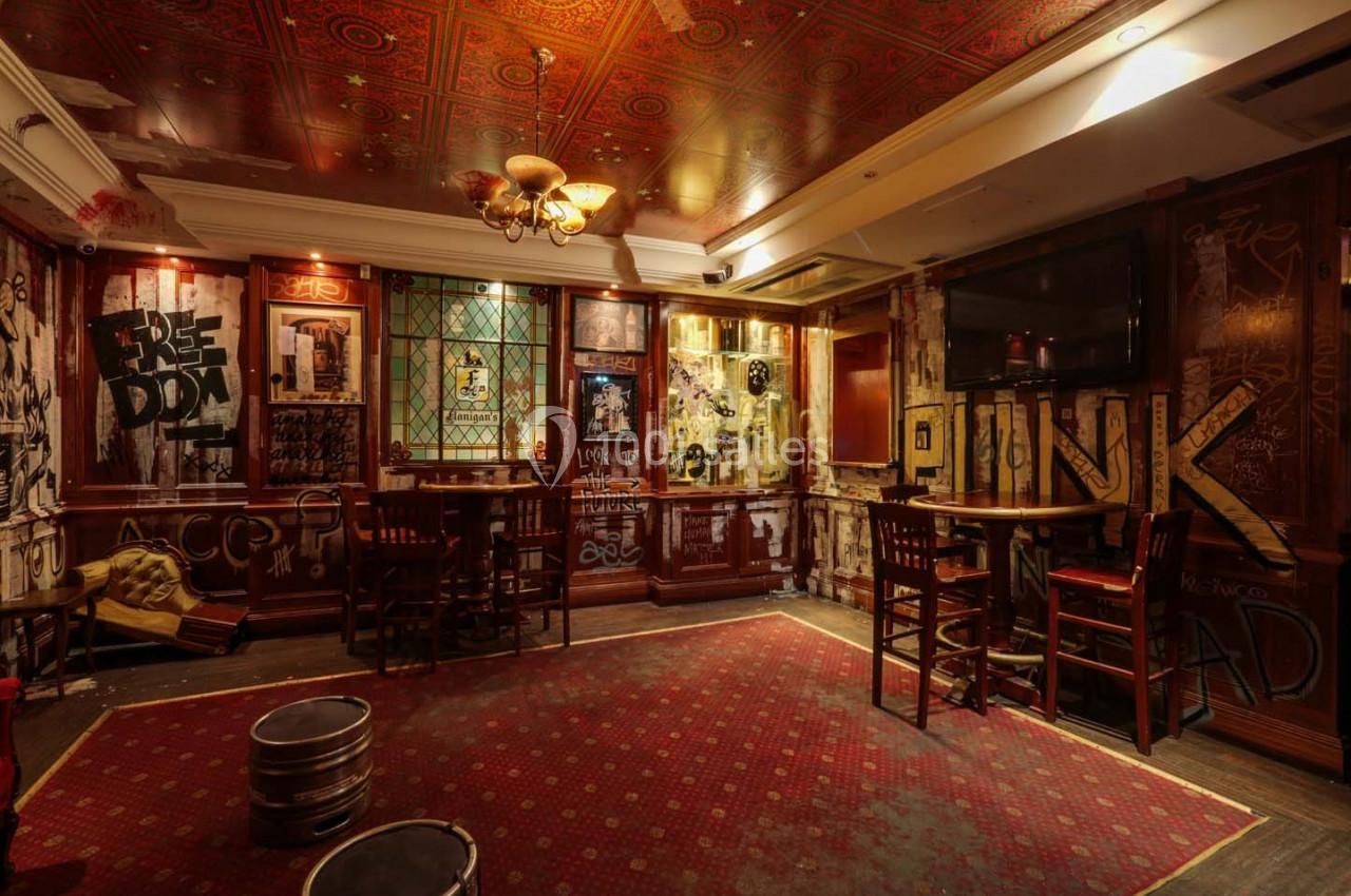 Salle de bar à la décoration vintage avec graffitis sur les murs, mobilier en bois et éclairage tamisé.